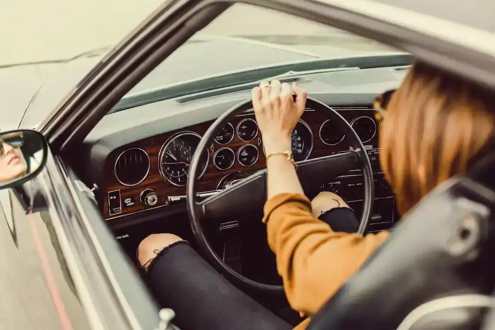 Femme au volant d'un véhicule de collection